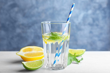 Glass with basil water and fruits on table