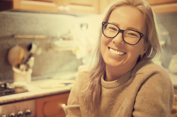 A woman is sitting in the kitchen and smiling. A housewife