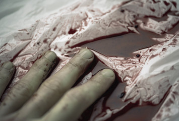 Arm of a died human in a small puddle of blood, place of an incident, background or texture
