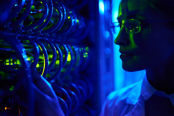 Closeup portrait of beautiful  female face by wire cables of server cabinet in neon light