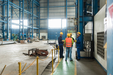 Group of four workers talking during break in the interior of an industrial hall