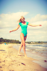 Fototapeta na wymiar Woman walking on beach wearing swimsuit