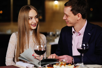 guy with a girl in a restaurant choose dishes from the menu