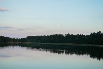  fishing rod on a background of calm lake water during a colorful sunset with a forested shore on the other side