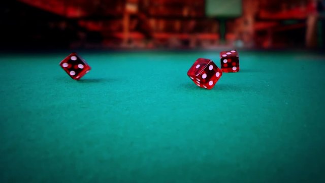 three red dice rolling on green game gambling table on light disco, shooting with slow motion, concept of sport recreation leisure game in the casino