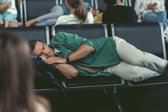 Jaded adult man is resting on seat at departure room