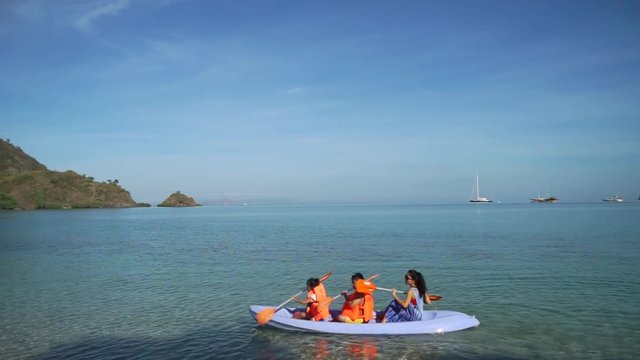 Young woman and kids enjoying holiday by canoeing on beach in Labuan Bajo at Flores Island close to Bali, Indonesia
