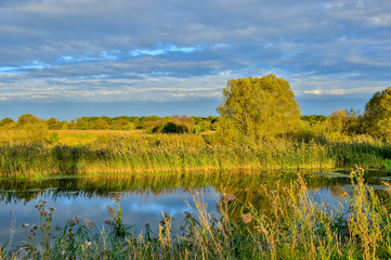 Colorful autumn landscape with a river and clouds