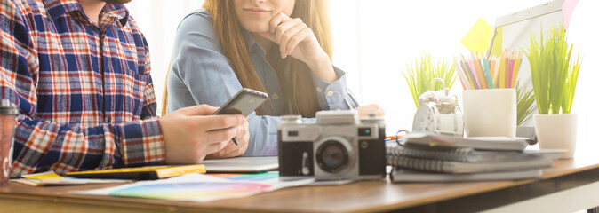 Two young creative designer colleagues using tablet at office