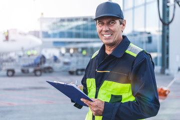 Cheerful worker writing document at airport