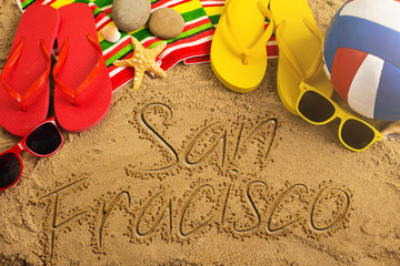 Summer concept of sandy beach, colorful thongs shoes, sunglasses, ball and inscription..