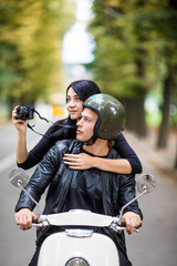 Fototapeta premium Happy tourist young couple on scooter. Woman making photo on camera while riding outdoors