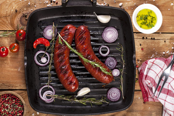 Grilled sausages in a pan on wooden background