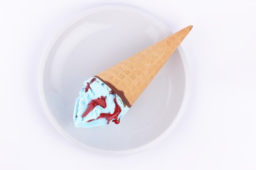 Ice cream in a waffle cup with blue stuffing and red jam on a white plate for designer