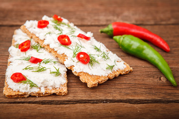 Bread with cottage cheese and chili pepper, with a bowl of cottage cheese with greens on a wooden background. Proper nutrition. Breakfast.