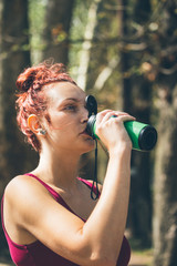 Fitness girl, race in nature, shaker, flask for protein in her hand, drinks from the flashes, takes extra strength and revives