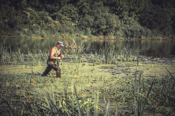 Obraz na płótnie Canvas hunter man breaking through swamp during hunting period