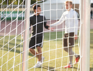Blurred silhouettes of players shaking hands during a football match.