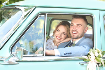 Happy wedding couple in car