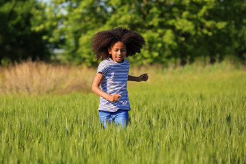 Fototapeta premium Little Afro American girl in green field