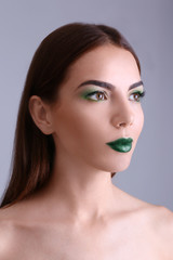 Naklejka premium Young beautiful woman with fancy green makeup on color background