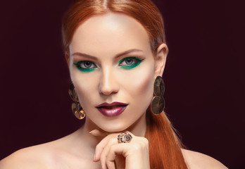 Fototapeta premium Beautiful redhead woman with bright green makeup on dark background