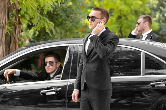 Handsome bodyguards near car outdoors