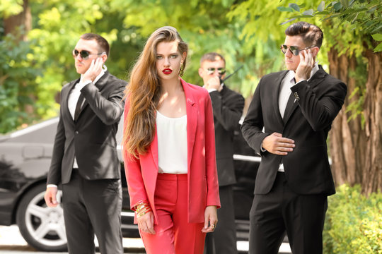 Young businesswoman with bodyguards outdoors