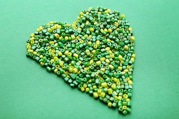 Beads in heart shape on green background
