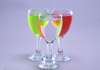 three glasses of wine containing different syrup colors