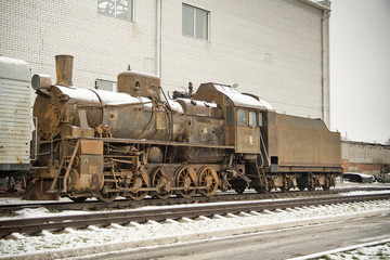 Naklejka premium Old rusty steam engine on railroad in winter