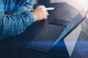 Man working at office.Businessman using electronic tablet keyboard-dock station. Reading text information on device screen. Horizontal side-view.