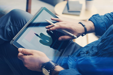 Fototapeta premium Businessman holding tablet on hand and using electronic pen while working at office.Touching finger tablet screen.Blurred background.Horizontal.