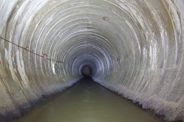 Underground river flowing in round concrete sewer tunnel. Sewage collector