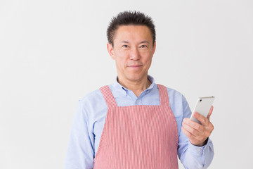 エプロンをしたミドル男性　スマホ
