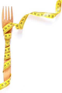Wooden fork wrapped in centimeter, concept of lose weight and healthy lifestyle, copy space for text on white