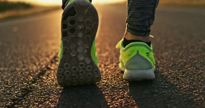 Woman Running on a Countryside Road at Sunrise. SLOW MOTION 4K DCi. Female jogger athlete training at dusk. Active healthy lifestyle concept. Cinematic sports shot. 