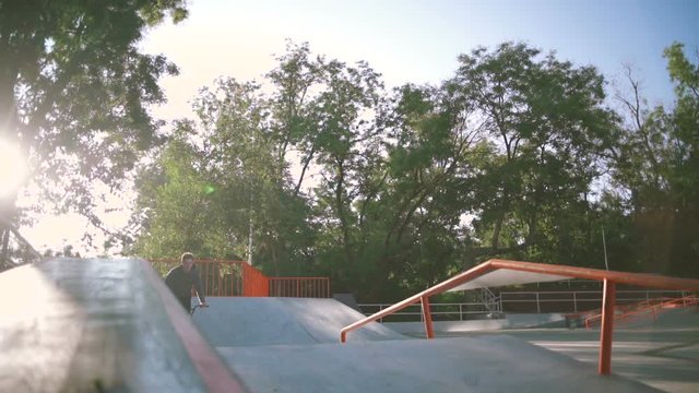 BMX rider doing tricks in extreme park during sunset, slow motion