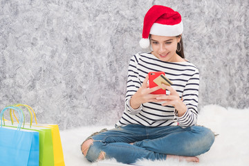 Obraz premium Beautiful young girl wearing a Santa hat holding lots of shopping bags in the festive season
