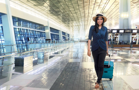 Beautiful asian woman walking while pulling blue suitcase