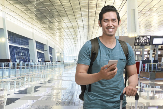 Young Asian Man Traveling With Suitcase And Mobile Phone