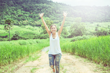Fototapeta premium Asian women travel relax in the holiday. Walk on the middle of the meadow road.