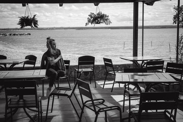 young beautiful woman in jeans clothes outdoors. portrait of a girl with freckles on her face, stylish girl in an empty cafe on sea beach, on a sunny summer autumn day.