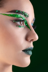 Young woman with creative makeup on dark background