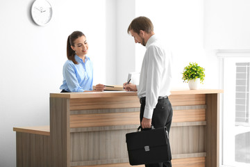 Young female receptionist meeting client in office