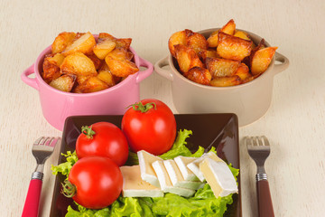 Breakfast from cheese, tomatoes, potatoes and all-over salad on a wooden table closeup.