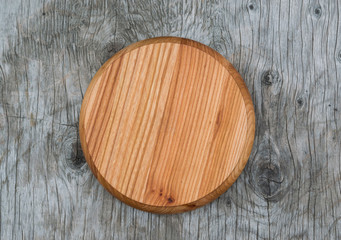 Round cutting board natural wood on the old wooden table vintage, closeup, top view