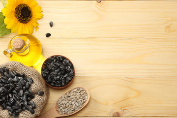 Sunflower oil, seeds and flower on light wooden background. top view with copy space