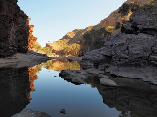 Fototapeta na wymiar Reflections in the dark waters of Ormiston Gorge with red glowing cliffs in the evening sun, Northern Territory, Australia 2017