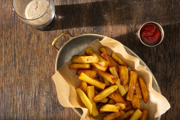 Pan of homemade french fries with ketchup and dark beer